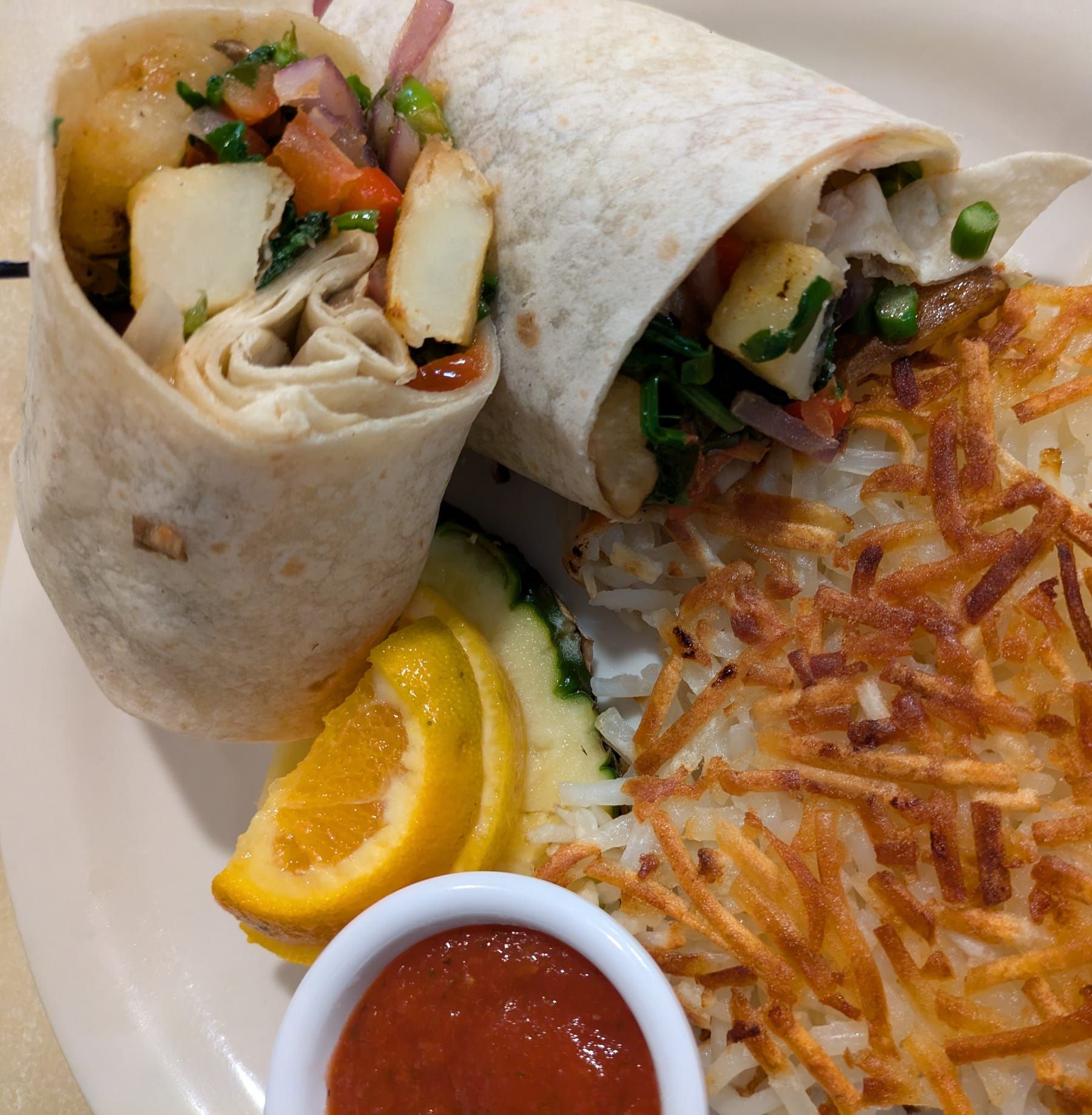 Imagen de referencia: burrito de desayuno partido a la mitad, con papas ralladas doradas y salsa.